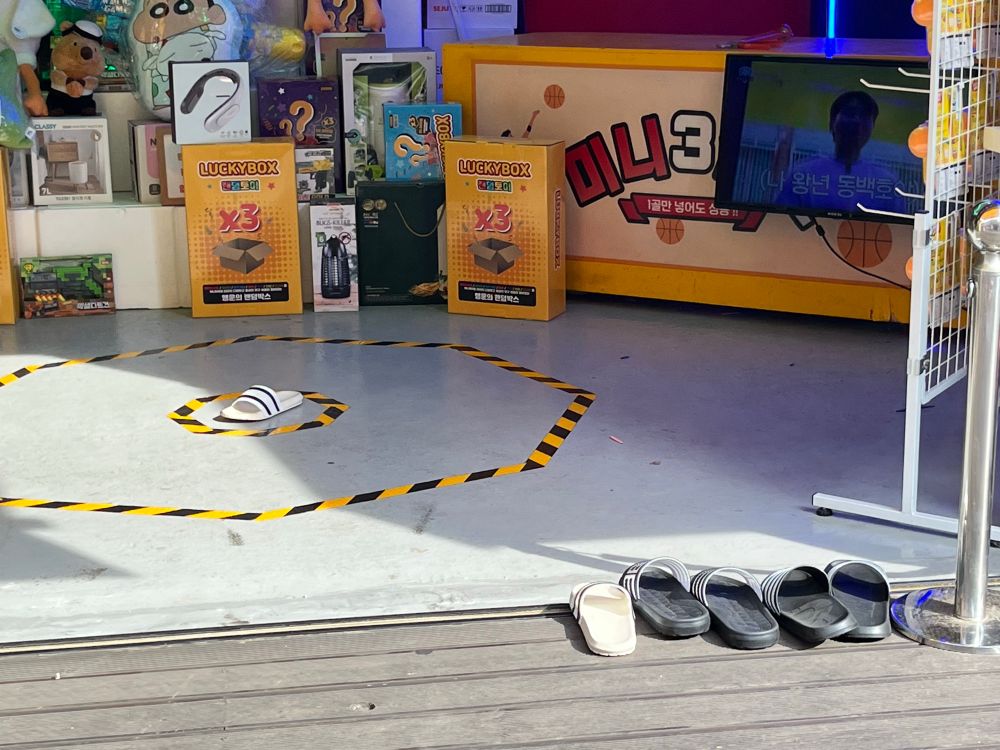 A bullseye outlined with yellow and black tape on the floor with a single slipper smack dab in the middle