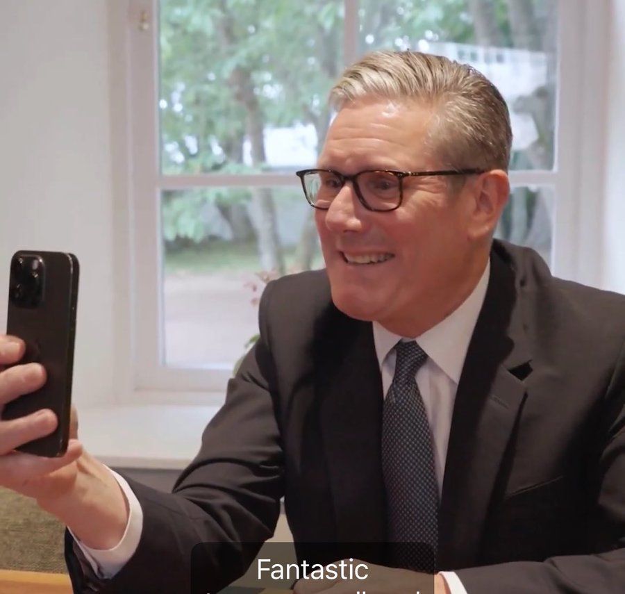 Sir Keir looking at his phone and smiling. "Fantastic," he says.