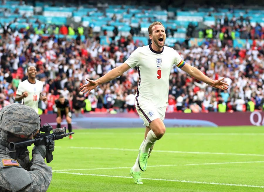 Harry Kane running while an American soldier points a gun at him.
