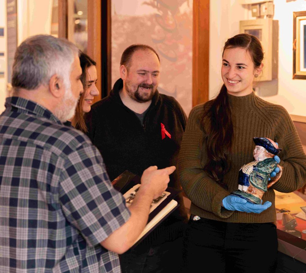 Photograph of curator showing others a toby jug from the War Poets Collection