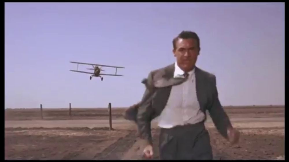 a man in a suit is running in front of a small plane