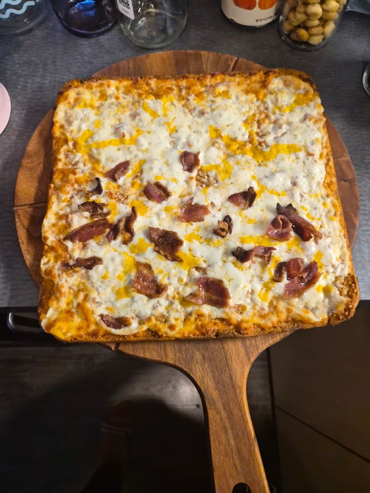 cooked CheezIt pizza with bacon bits added to half the pizza