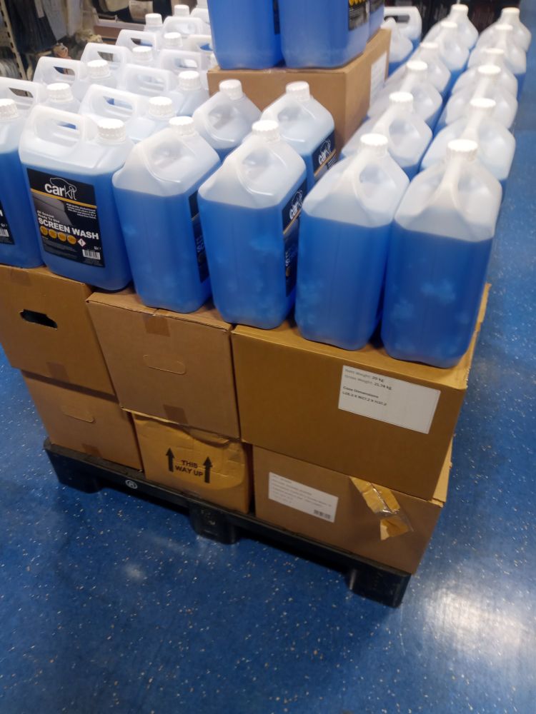 A stack of plastic washer fluid bottles. The fluid is blue. 