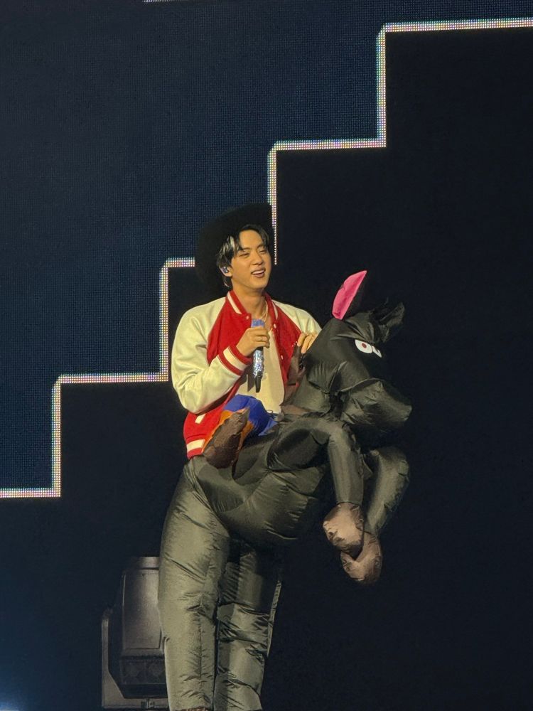 Jin in a costume of a cowboy riding a horse.