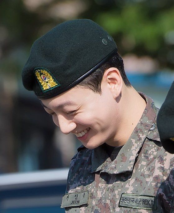 Close up of BTS' Jungkook smiling during his discharge from the military. He is wearing his uniform.