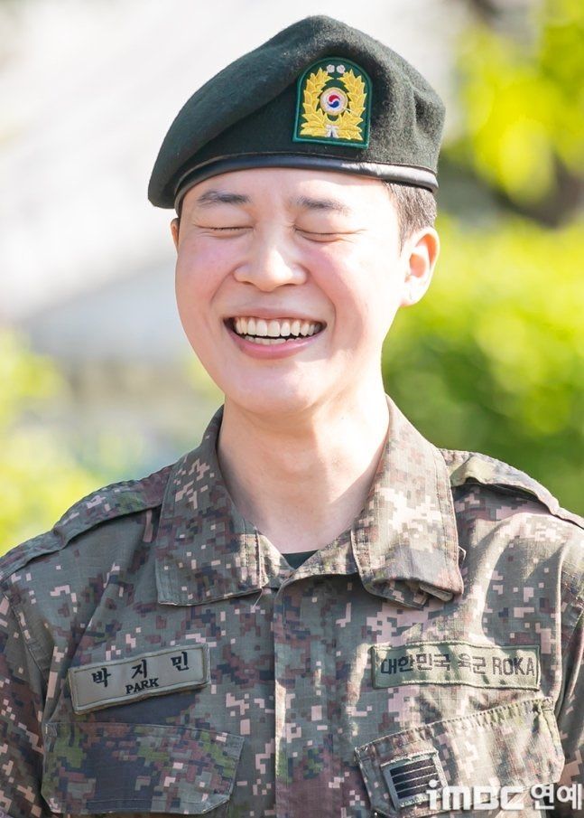 Close up of BTS' Jimin smiling during his discharge from the military. He is wearing his uniform.