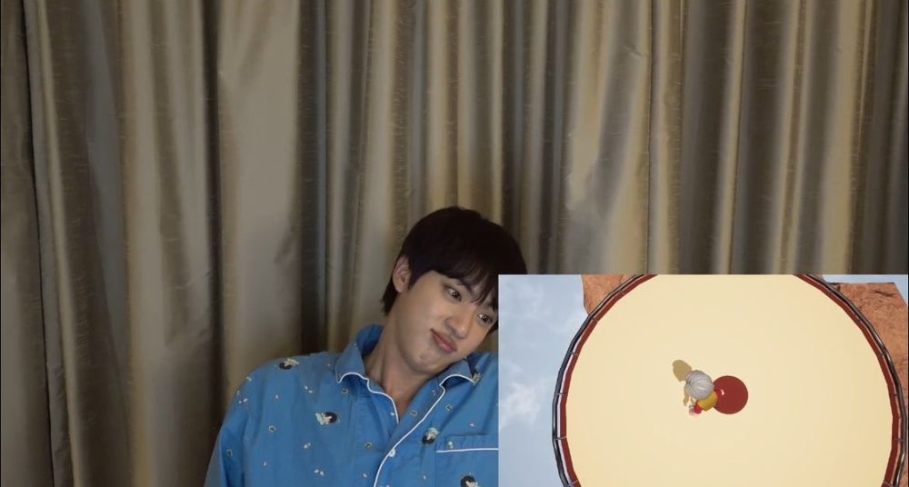 BTS Jin during his Weverse Live. He is wearing light blue jammies, his good day pj's. He is pouting because he lost the game he was playing.