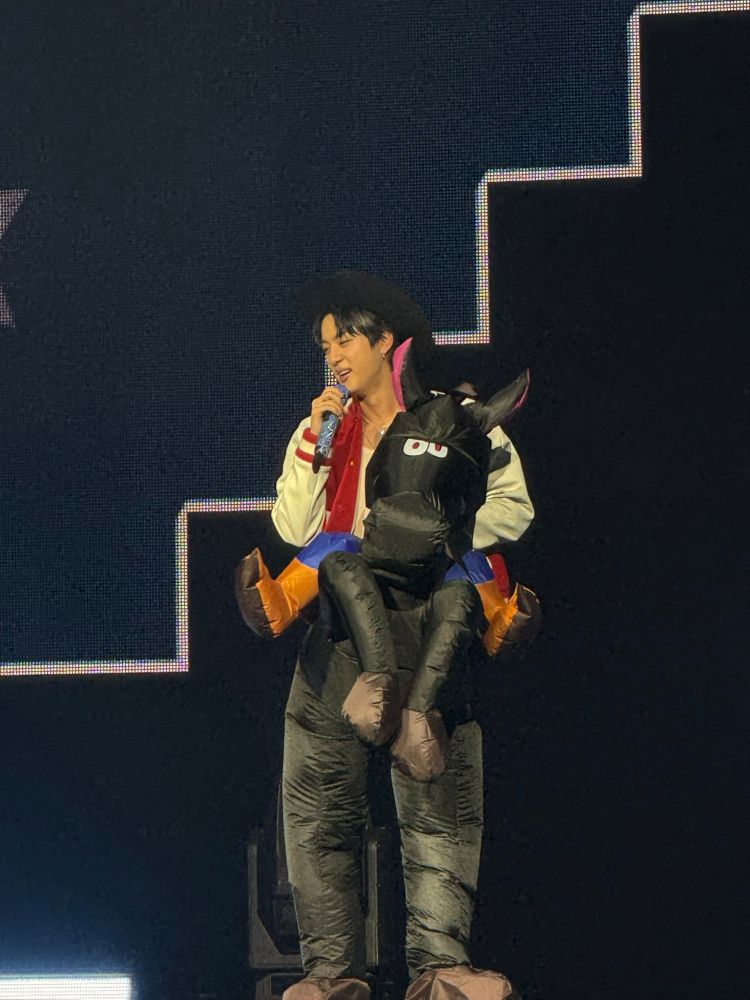 Jin in a costume of a cowboy riding a horse.