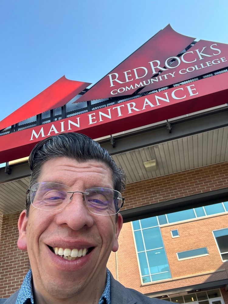 Jay Harris standing in front of the main entrance of Red Rocks Community College.