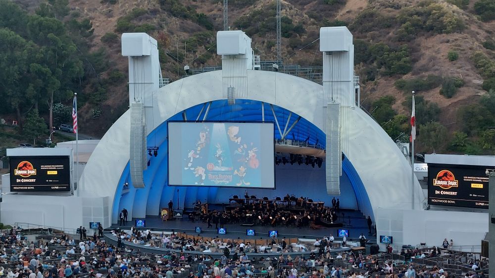 The stage of the Hollywood Bowl at sunset, with the artwork for "Bugs Bunny at the Symphony" showing on a screen in front of the stage.
