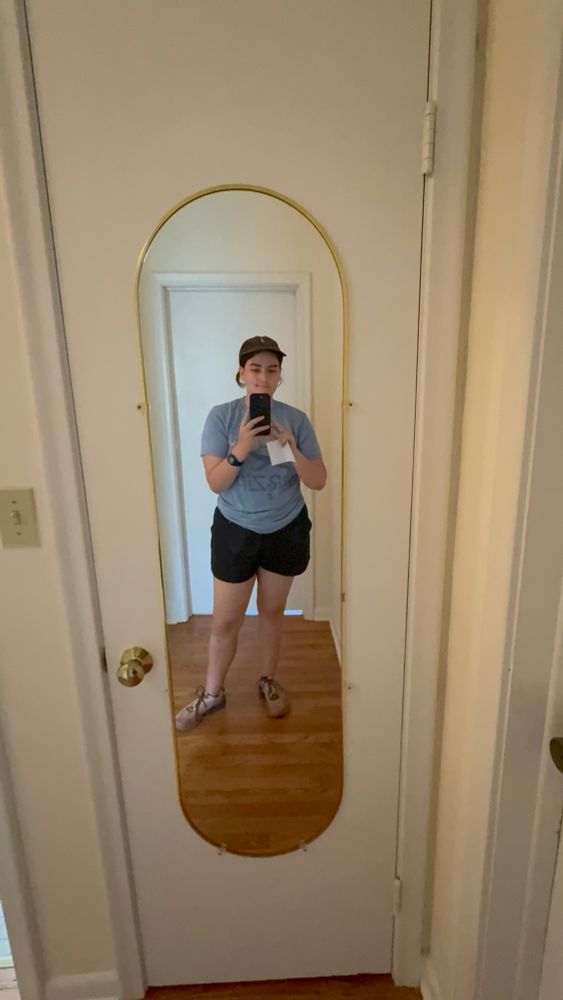 Em wearing black shorts, a blue t-shirt and a Palestine hat in a mirror selfie 