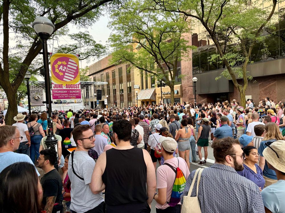 large crowd around the stage out for pride in ann arbor. normally cars drive here but this is better! there’s a banner for summer streets when cars are banned thursday-sunday june-august. but it should be more!