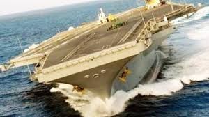 Image of an aircraft carrier performing a hard turn.
