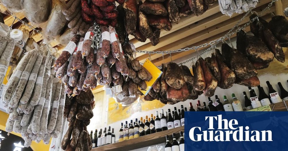 a lot of dried meats hanging from a shop with wine bottles on a shelf - guardian logo at the bottom right
