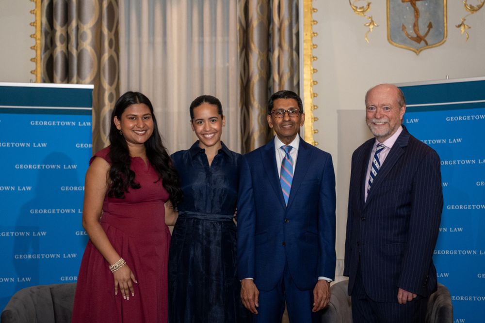 Amritha Ramalingam, Yasmeen Rose, Chief Judge Sri Srinivasan, and Dean William M. Treanor pose together in front of Georgetown Law-branded step-and-repeat banners.