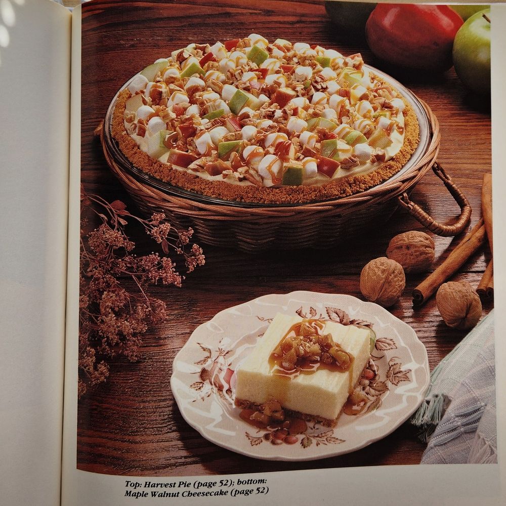 Photo of Harvest Pie, which is a graham cracker crust absolutely overflowing with chopped apples, nuts, and mini marshmallows, covered in caramel sauce. Also pictured at the bottom is Maple Walnut Cheesecake.