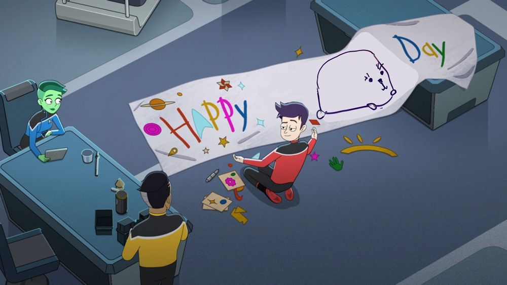 Screen grab from Star Trek: Lower Decks that has been edited. It shows Tendi and Rutherford at a table, while Boimler is on the floor painting a banner in a childlike style. The original banner said Happy Freeman Day, but the word Freeman has been edited in this version and replaced with the drawn image of Moopsy from the post that is being replied to with this image.