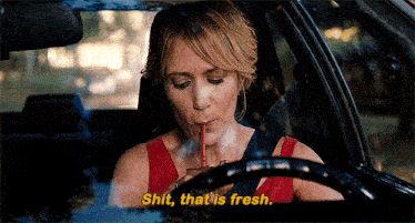 Annie from Bridesmaids driving a car and taking a sip from a drink. She puckers her lips after and says with satisfaction, "Shit, that is fresh."