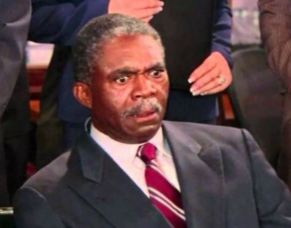 Still image from How I Met Your Mother, Man in a suit and tie with wide eyes and raised eyebrows, looking shocked or surprised.