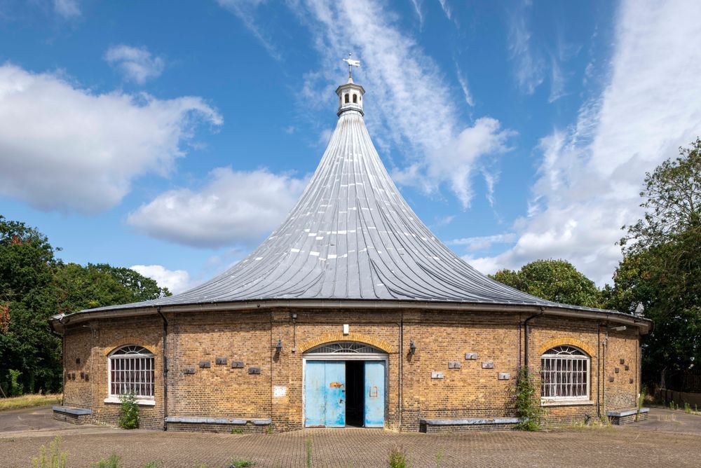 A photograph of the Rotunda viewed from the south, taken head on with blue skies above, trees either side of the building, and the doors ajar. [Chris Redgrave © Historic England Archive, DP487796]