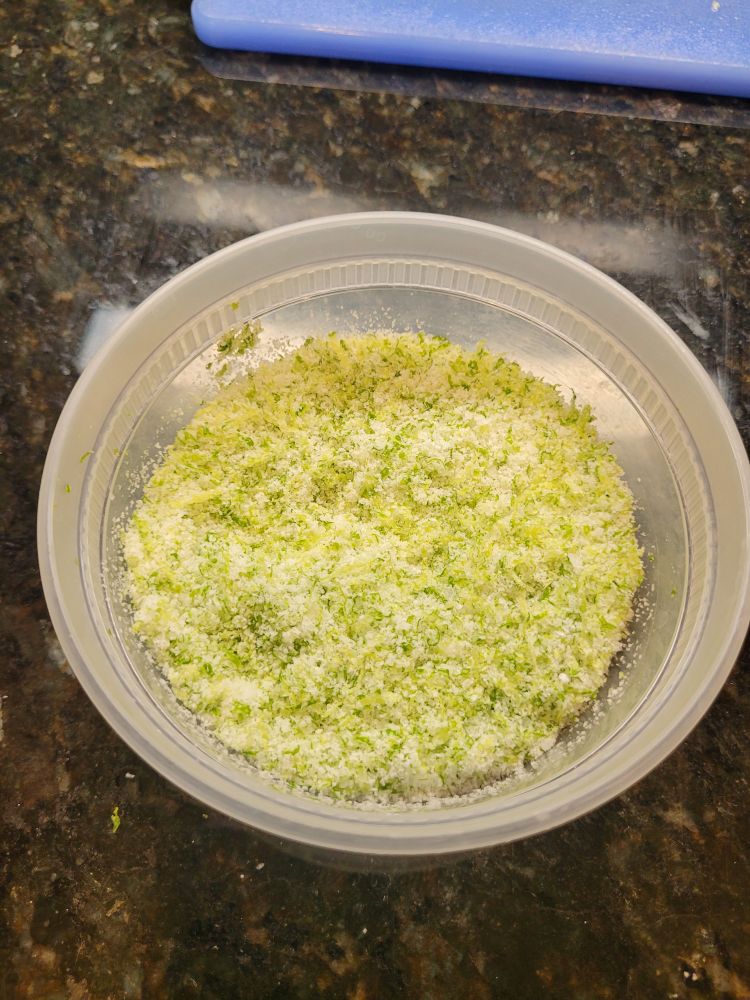 Small plastic container containing a light green powdery substance. This is the salt with lime zest mixed in.