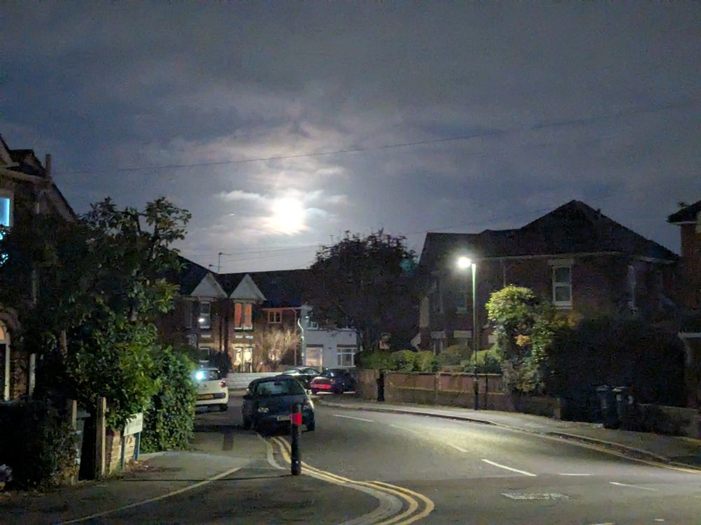 Image shows an incredibly bright full moon - a November 'Beaver Moon' over a typical British suburban street at night time