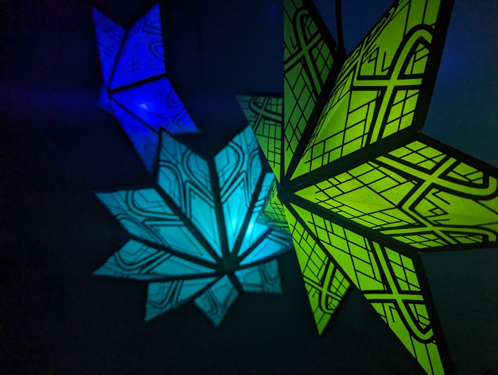 3 star lanterns made from paper glowing in different colors