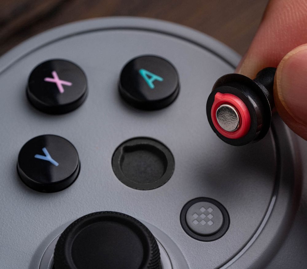 A face button on a controller being pulled. A magnet is visible on the back. 