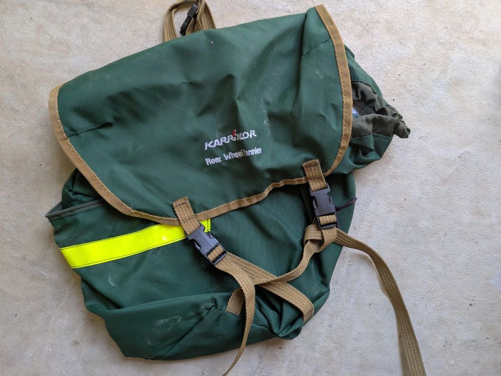 A very old green cycle pannier made by Karrimor, on its way to the dump. 