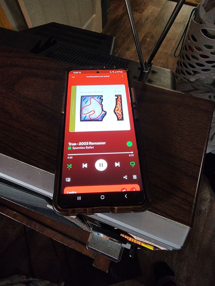 a photo of my old phone playing 80's music on Spotify, sitting on top of an OLD CRT TV with 2 dials and rabbit ear antennas. The song is "True" by Spandau Ballet