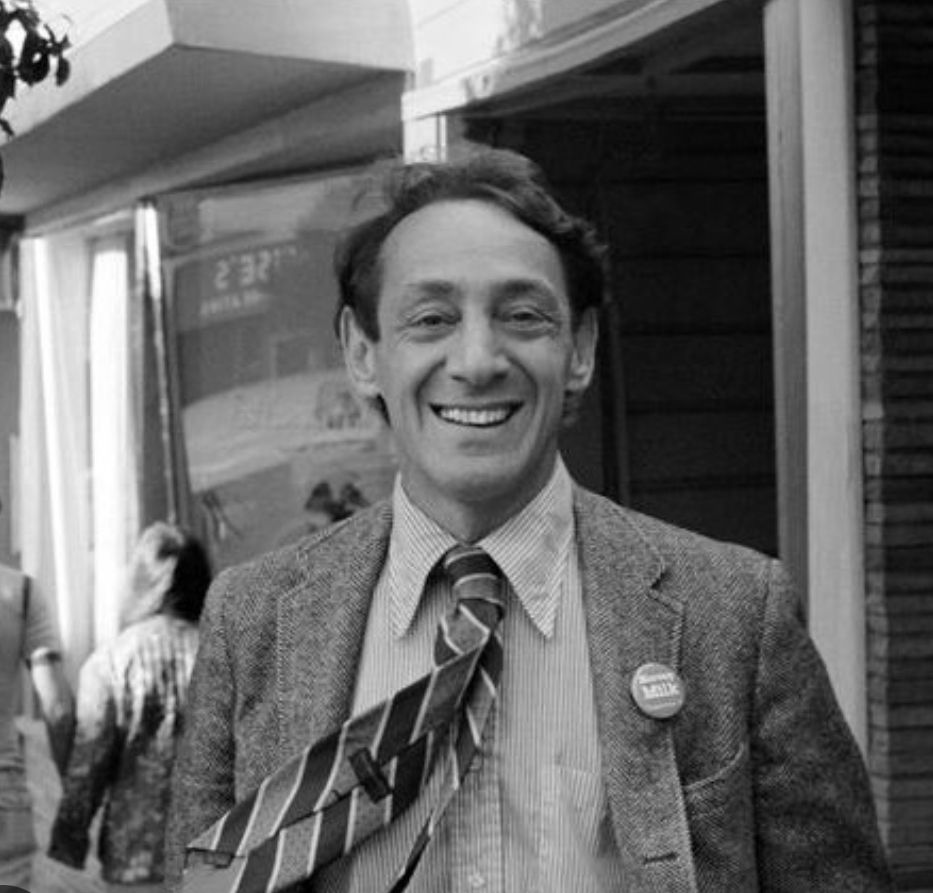 Smiling Harvey Milk outdoors wearing a tie. 
