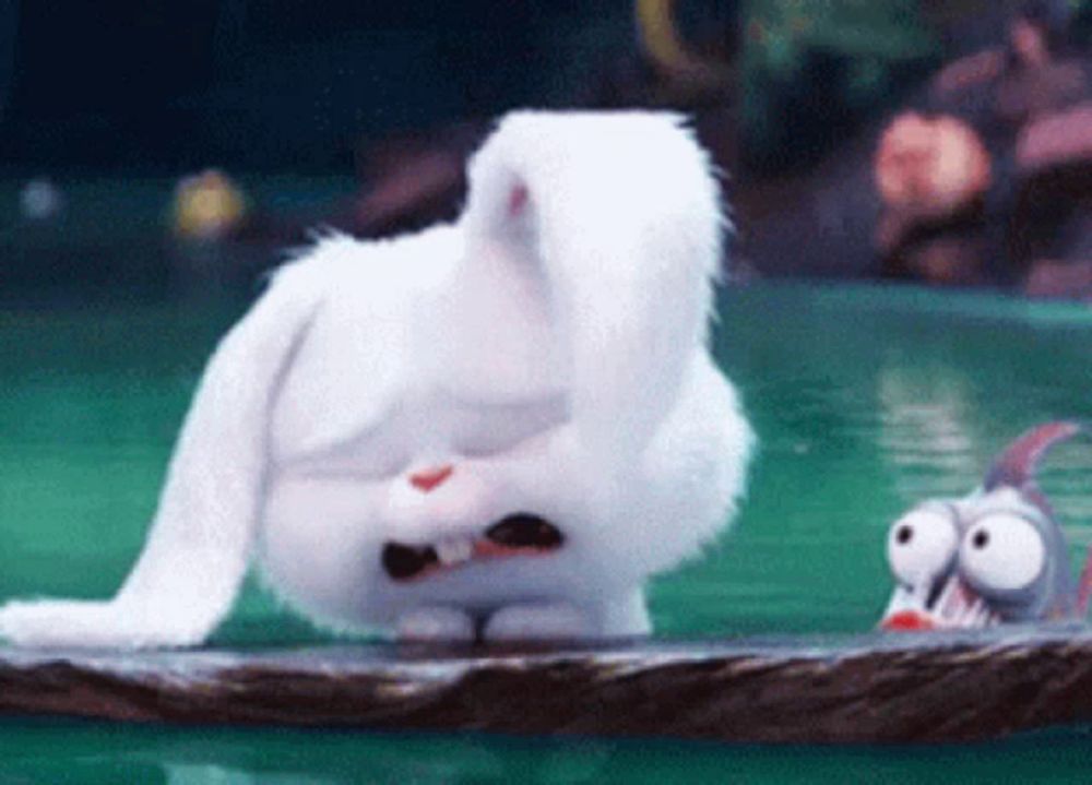 a white stuffed rabbit is sitting on a rock in the water .