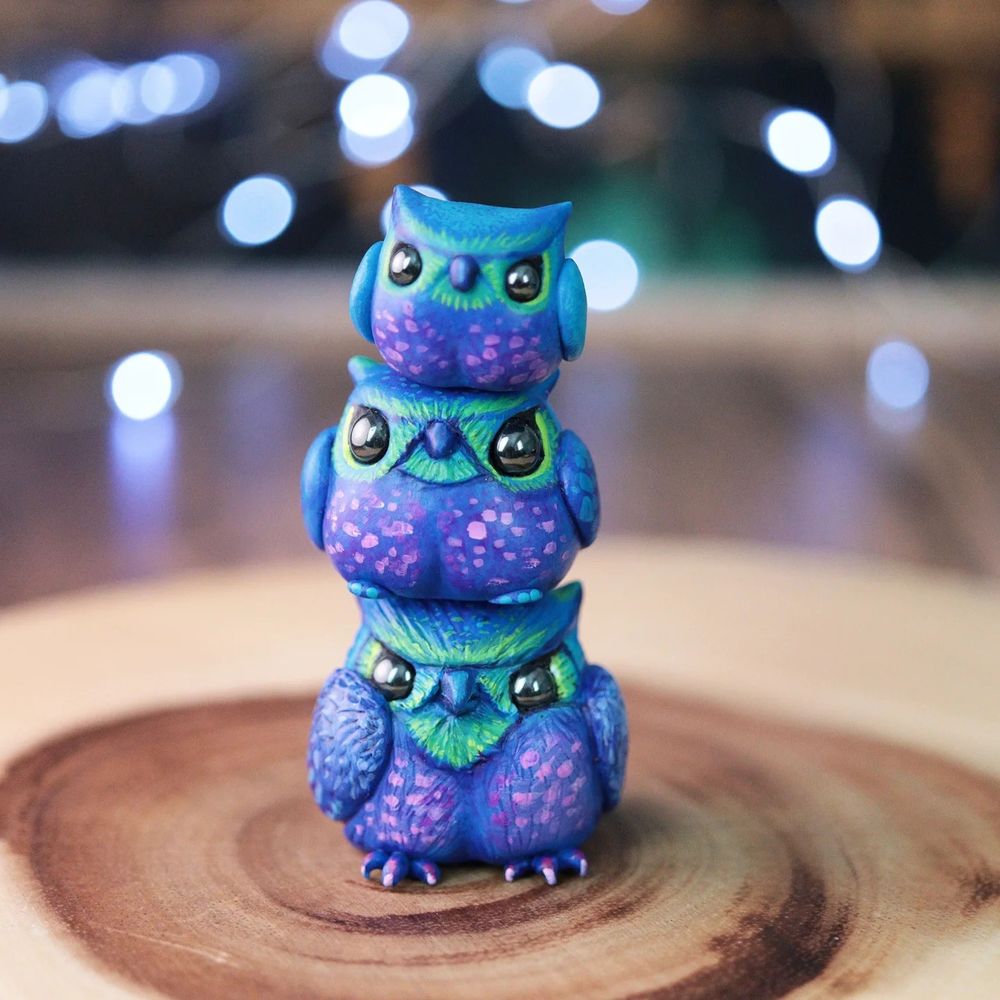 3 brightly colored grumpy owl figurines stacked on top of each other. 