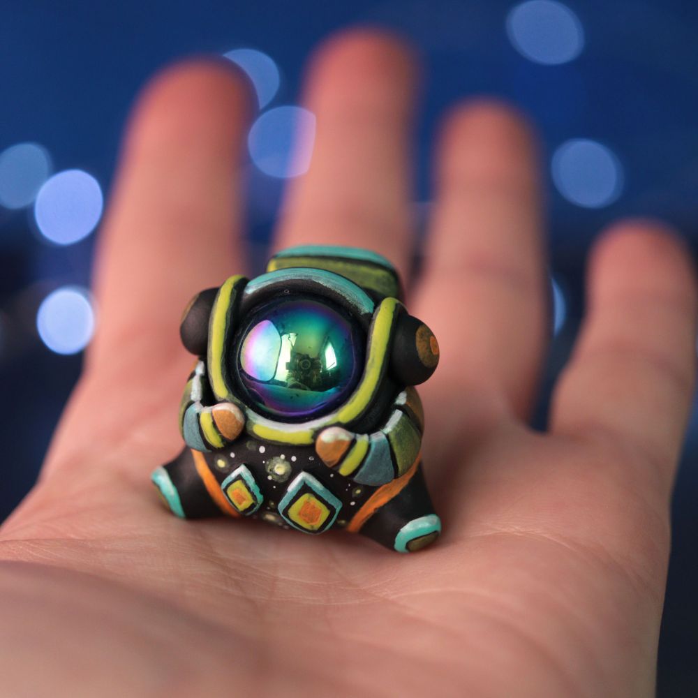 A hand holding a colorful astronaut figurine with a shiny helmet and a fun design on their space suit