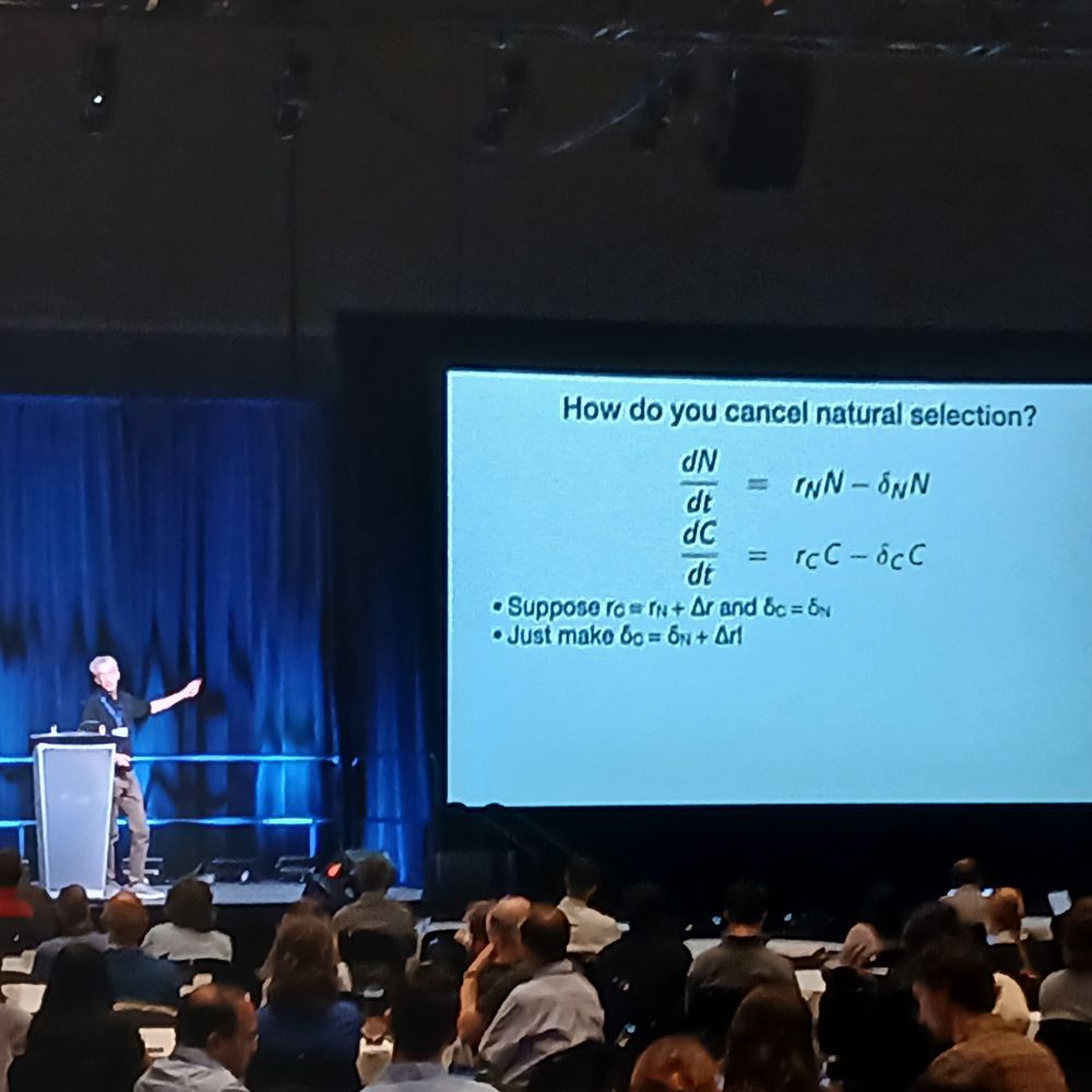 Photo of Fred Adler presenting a slide with the title "How do you cancel natural selection" in refefence to indrstanding cancer immunology.