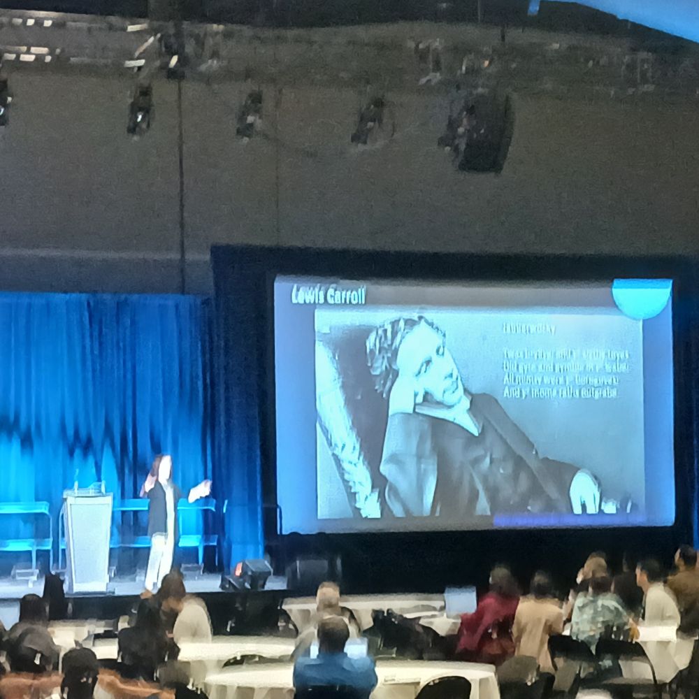 Photo of Susan Manrubia presenting the first slide of her plenary talk at the SMB meeting (featuring a picture of Lewis Carroll).