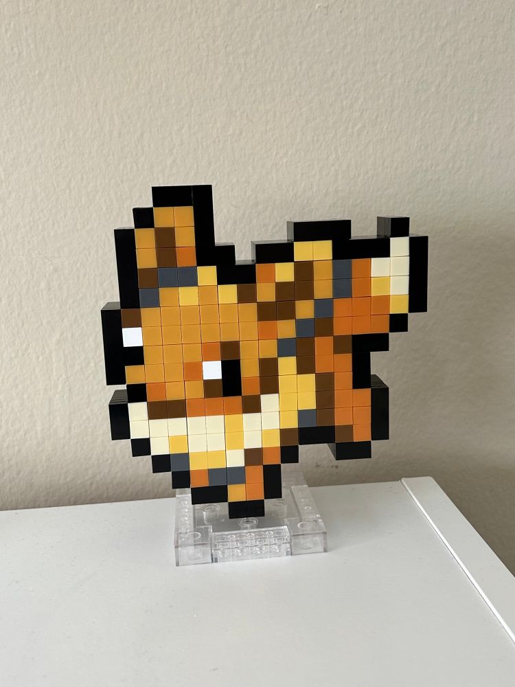 an off-brand LEGO set of the Pokémon Eevee’s sprite, fully assembled on a clear display stand.