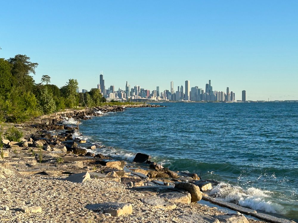 Rocky shore of Lake Michigan with the skyline of Chicago visible in the distance.