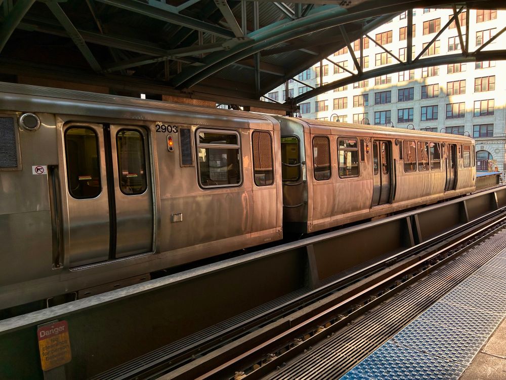 the end of a CTA “L” train at the platform under a station canopy, seeming to almost glow orange in reflected light.