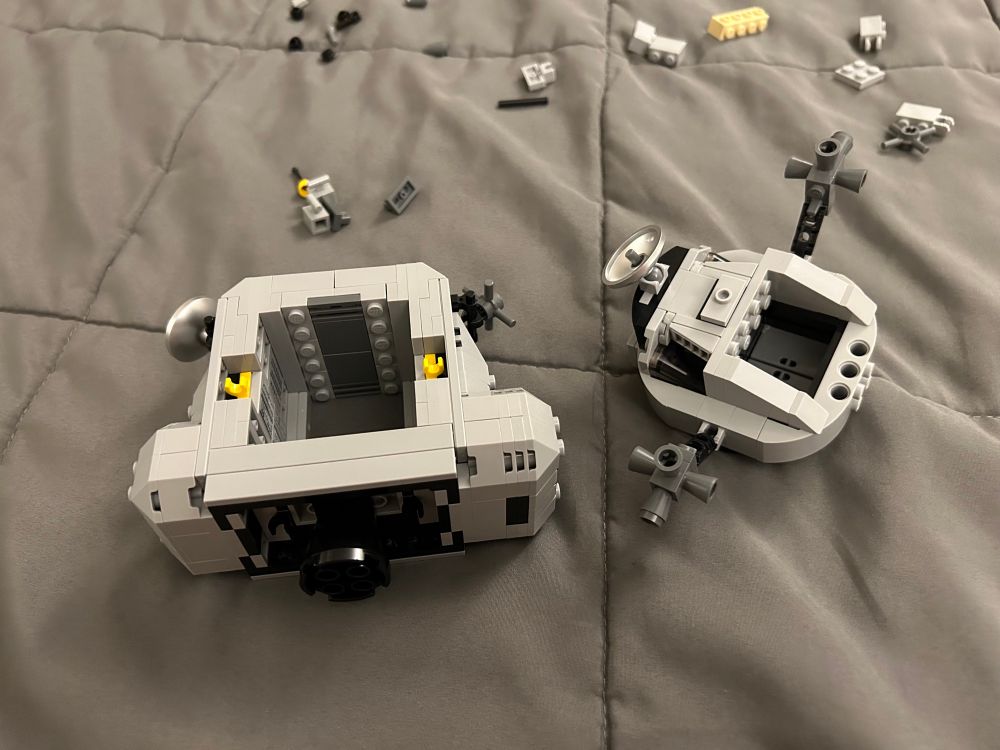 A partially-assembled LEGO set laid out on a gray quilted surface.