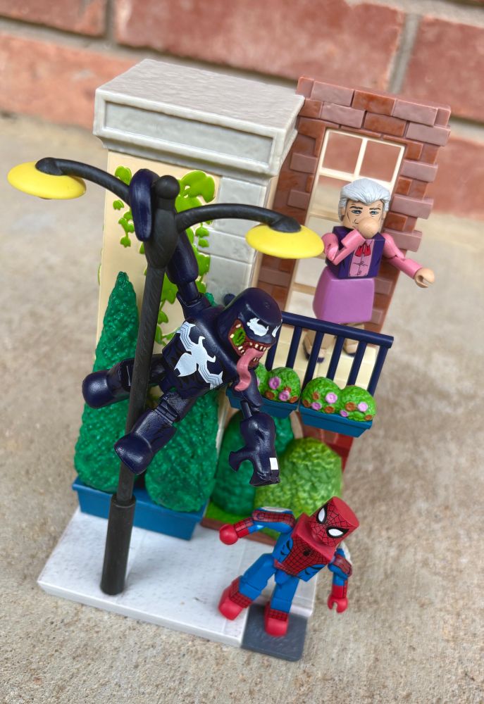Marvel Minimates figures of Venom, Spider-Man, and Aunt May posed on a Jazwares Pokemon Select cityscape playset.