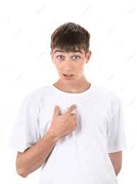 A guy in a white t-shirt, pointing to himself, with a surprised expression on his face, as if to say, "me?"