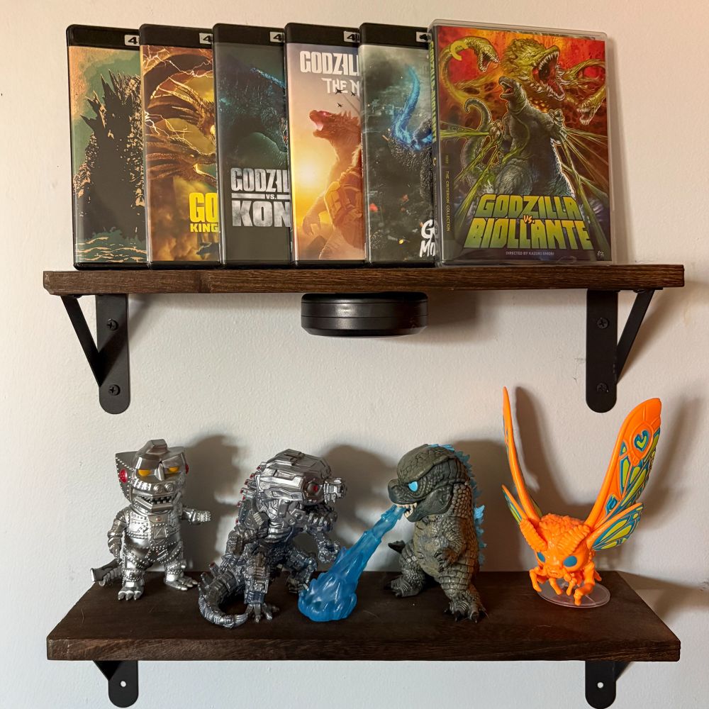 Two shelves with Godzilla 4K films on the top shelf including Godzilla Minus One, Godzilla vs. Biollante, and the entire Legendary universe while two versions of Mechagodzilla Funko POPs square off against Godzilla and Mothra POPs.