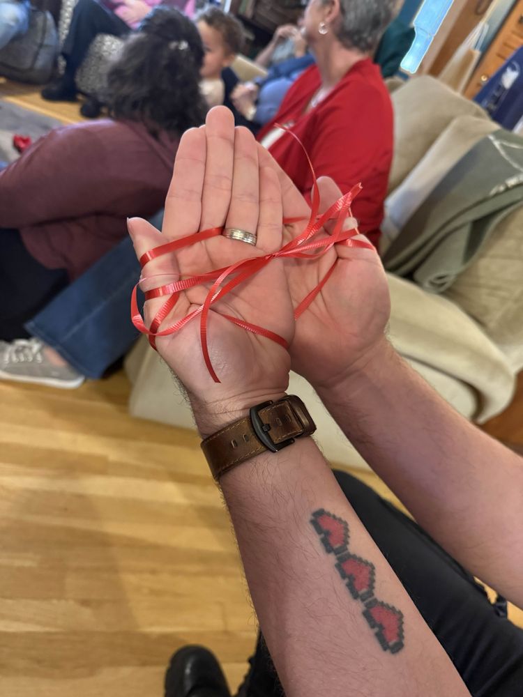 Chris’s hands looped together in a pattern of red gift ribbon.