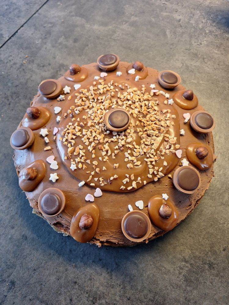 A cake decorated with caramel, toffifays, sprinkles and hazelnuts