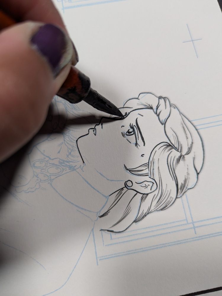 A dip pen touches watercolor paper, drawing a beautiful young woman.