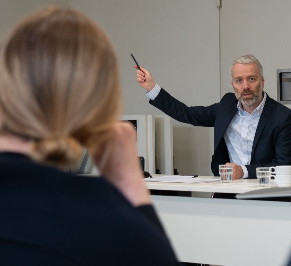Dr. Christian Pfeffer-Hoffmann (Leitung und
Geschäftsführung von Minor Projektkontor für Bildung und Forschung) zeigt mit dem Stift in Richtung Bildschirm, wo die Präsentation der Machbarkeitsstudie gezeigt wird. 