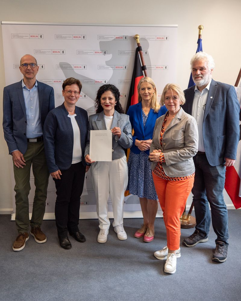 (v.l.n.r.) Dirk Arp-Stapelfeldt (AWO Berlin), Ulrike Kostka (Caritas Berlin), Cansel Kiziltepe (Senatorin für Arbeit, Soziales, Gleichstellung, Integration, Vielfalt und Antidiskriminierung), Andrea Asch (Diakonie Berlin-Brandenburg), Gudrun Sturm (DRK Berlin) und Martin Hoyer (Parität Berlin). Senatorin Kiziltepe hält den Vertrag in den Händen.