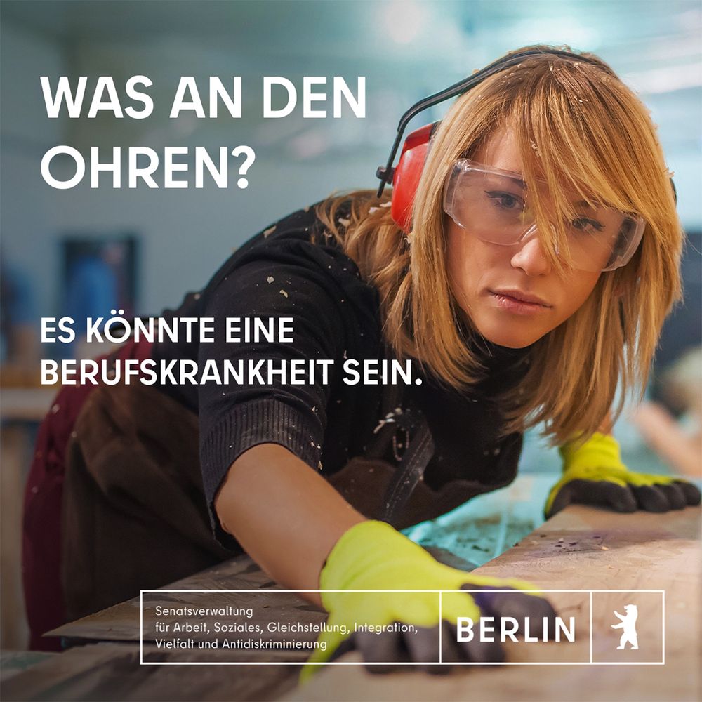 Eine junge Tischlerin mit Schutzbrille beugt sich über ein Holzbrett, das sie mit beiden Händen in Handschuhen festhält. Der Text: "Was an den Ohren?  Es könnte eine Berufskrankheit sein"
