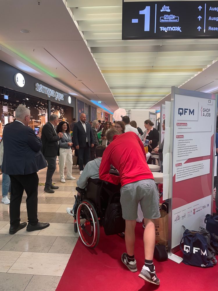 Senatorin Cansel Kiziltepe mit Bezirksbürgermeister Frank Bewig beim Rundgang durch die Jobmesse. Im Vordergund ein Besucher im Rollstuhl und sein Begleiter stehen am Stand vom Unternehmen QFM und hören zu. 

Foto: © JOB POINT Berlin